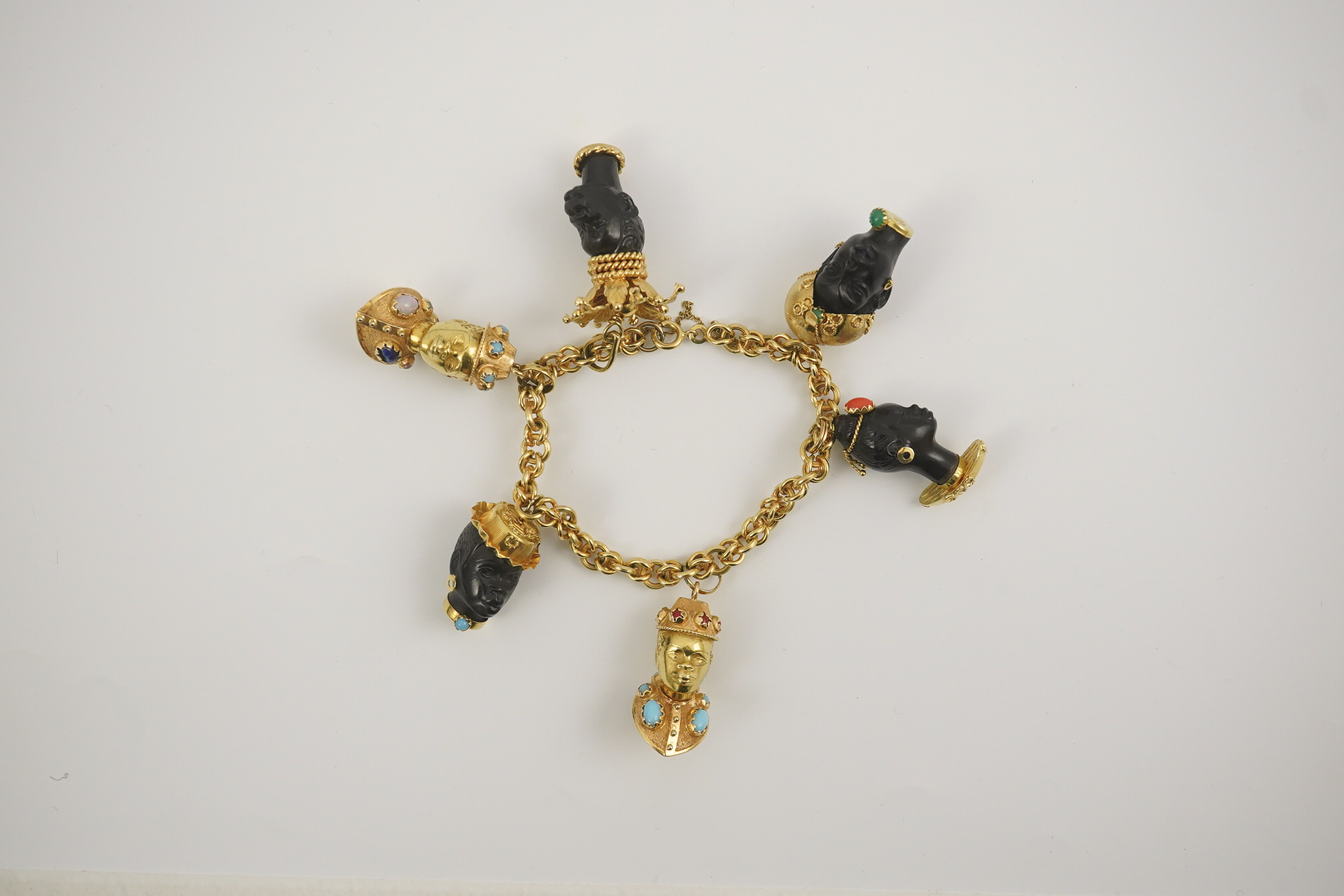 A late 20th century Italian 18k gold charm bracelet, hung with six assorted Italian 18k gold and gem set mounted blackamoor busts, together with a matching brooch